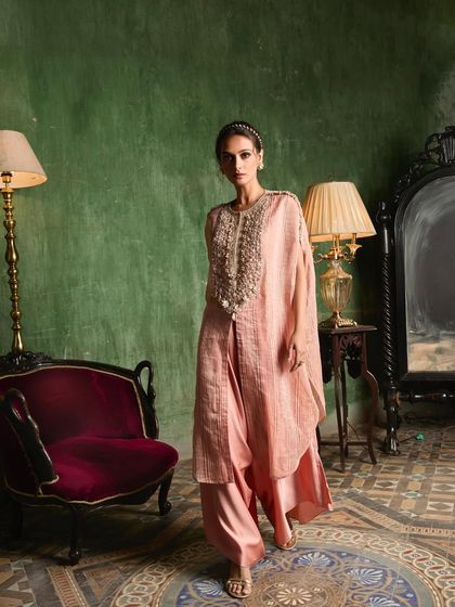 A model walks in a beautiful pink layered ensemble with a heavily beaded yoke, showcasing its movement and grace.