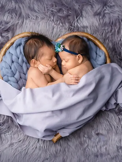 Two newborn twins, a boy and a girl, sleeping together in a heart-shaped basket. This is a beautiful and symbolic way to capture their connection from the very beginning.