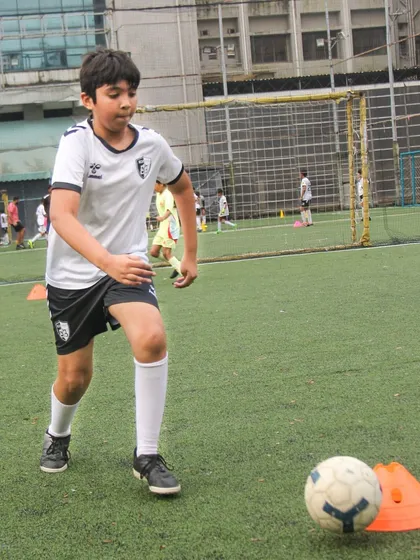 A player dribbles around a cone marker, an exercise designed to improve close control and the ability to change direction quickly.