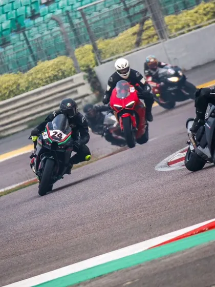 A pack of four riders, including a Ducati and an Aprilia, dive into a corner at the Buddh International Circuit. This shot shows the variety of superbikes and the intensity of group riding at our events.