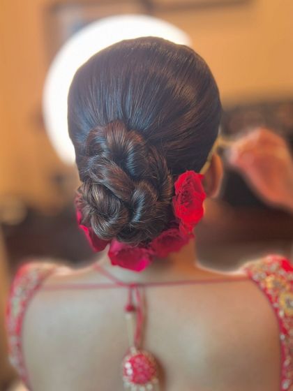 A beautiful braided bun with red roses tucked in, combining texture and color for a stunning bridal updo.