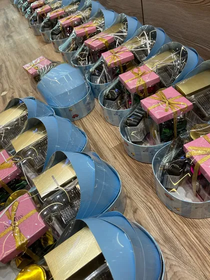 A row of my signature blue cradle-shaped gift baskets, all packed and ready to be sent out for a baby boy announcement.