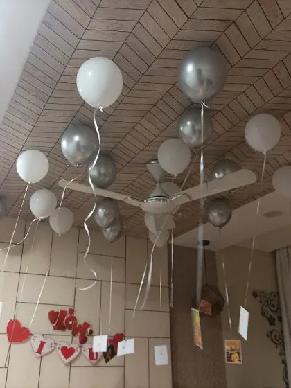 A simple yet personal anniversary decoration. Silver and white balloons float on the ceiling, with photos of the couple hanging from the ribbons.