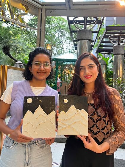 Two friends showing off their matching mountain-themed texture paintings. It's a great activity to do with a loved one.