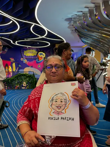 An older woman proudly displays her caricature at a family gathering, showing that the fun is for all ages.