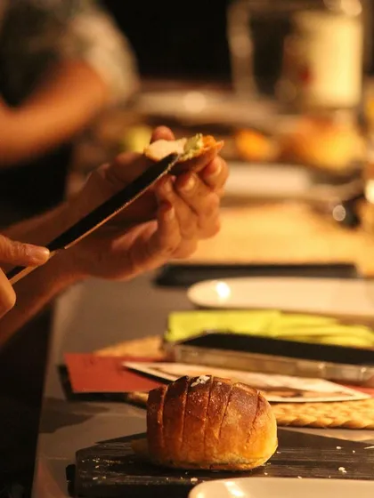 A guest enjoying the bread course from 'The Wonder Years' dinner, featuring coriander chili lime and Goan sausage butter.