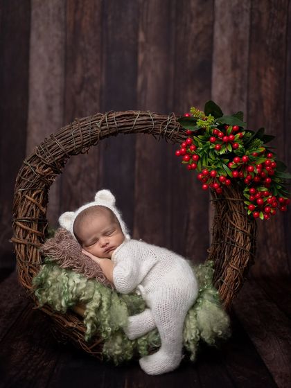 A wider view of the winter wreath setup, showing the beautiful contrast between the dark wood, green moss, and white outfit.