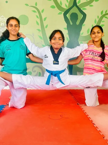 Teamwork makes the dream work. Two students support a third in a full split, showcasing both flexibility and camaraderie.