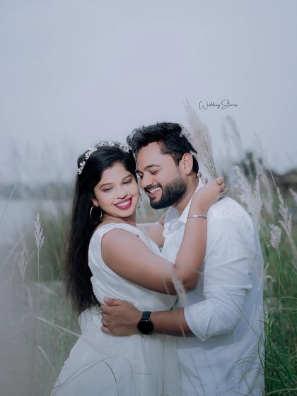 A happy and intimate embrace in a field of tall grass. The couple's white outfits create a fresh and clean look against the natural scenery.