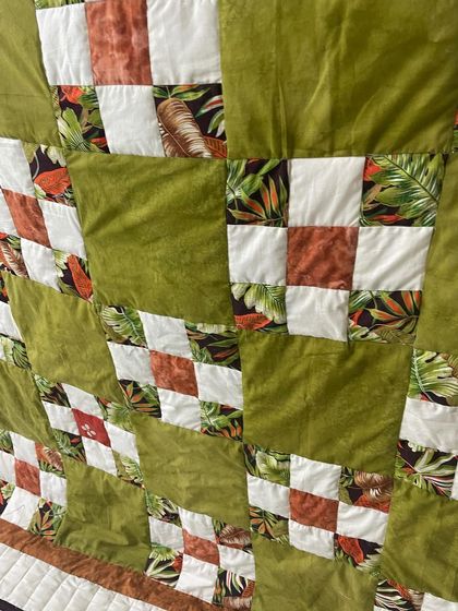 A detailed shot of the front of the young student's quilt, showing the combination of solid and patterned fabric squares.