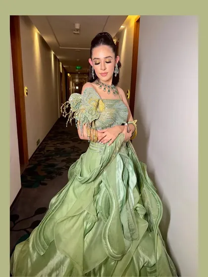The same gown, showing the intricate details of the shoulder embellishment and the flowing, layered skirt.