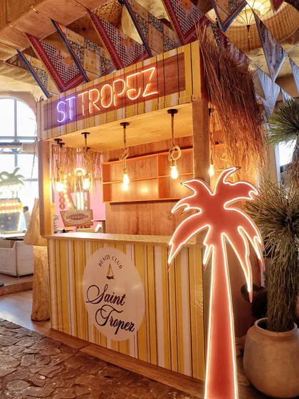 A custom-built 'Saint Tropez' beach club bar, complete with a neon palm tree and a logo for the event.