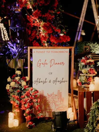 The welcome sign for the 'Gala Dinner', styled as 'A Toast to Tomorrow'. The sign is surrounded by candles and lush red floral arrangements.