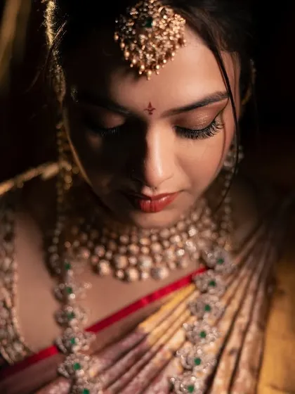 A dramatic, close-up portrait of the bride, using light and shadow to highlight her emotion and the intricate details of her wedding look.