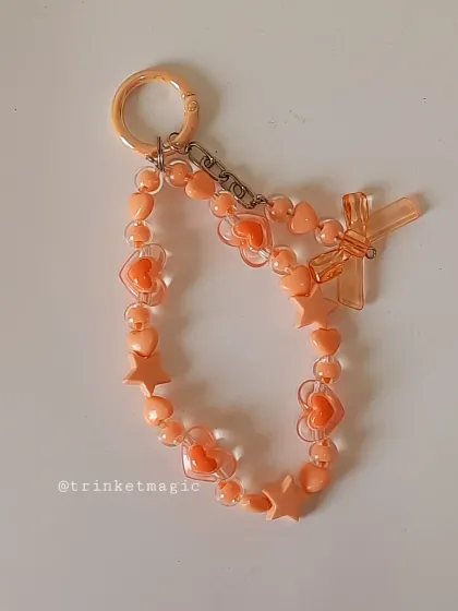 A close-up of the orange pastel beaded keychain. The warm, sunny color is perfect for brightening up your bag or keys.