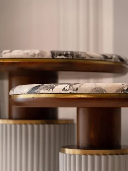 A close-up of the tiered side tables, showcasing the brass detailing and the rich texture of the materials.