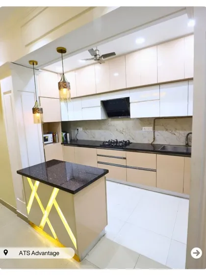 A modern kitchen with an island featuring a backlit panel. The neutral-toned cabinets and black granite countertop create a sleek and sophisticated look.