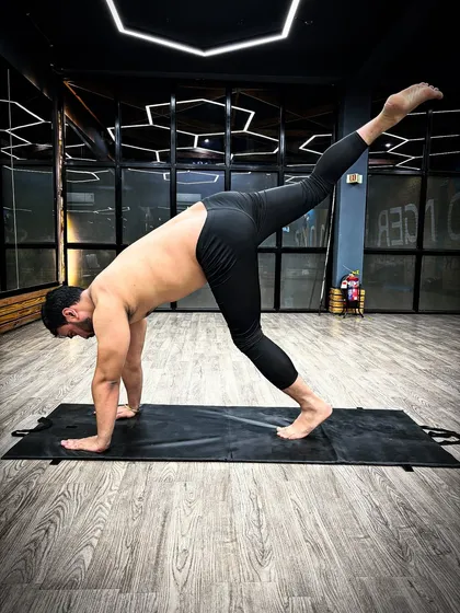 Practicing a variation of the Three-Legged Downward-Facing Dog pose. This asana is great for stretching the hamstrings and strengthening the upper body.