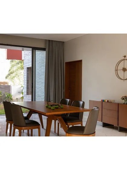 The dining area in the "Solid | Void | Solid House" is an elegant space that opens onto a side garden, allowing for cross-ventilation and a connection to nature during meals.