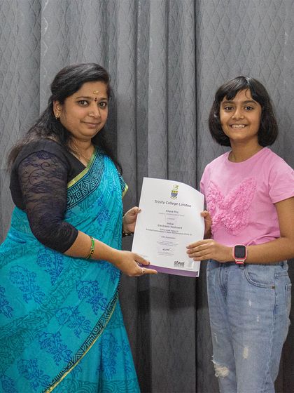 A student receives her Trinity College London certificate from her teacher.