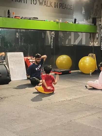 An instructor leads the kids' class in stretching exercises. Flexibility and mobility are important parts of their overall physical development.
