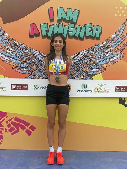 "I am a finisher." Posing in front of the finisher wall at the Vedanta Delhi Half Marathon. This image represents the ultimate goal for every runner: crossing the finish line with pride.