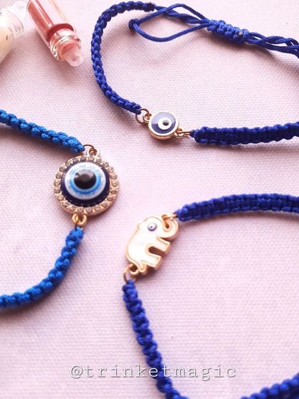 Simple, elegant, and protective. This collection of evil eye Rakhis features an elephant charm for good luck and a classic round evil eye charm, all on a traditional blue thread.