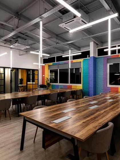 This open-plan workspace features a custom installation of suspended LED tubes. The arrangement is designed to provide excellent, uniform light for working while creating a sense of energy and movement that reflects a modern, dynamic company culture.