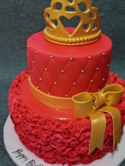 A bold and beautiful princess cake in a striking red. This two-tiered design features a quilted pattern, a large gold bow, and a crown topper for a dramatic effect.