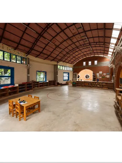 This large, multipurpose hall is defined by its high, arched roof and abundant natural light from the windows and skylights. The open floor plan provides flexibility for various activities, from group lessons to free play.