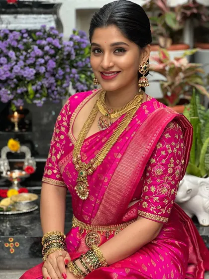 This bride is a vision in a vibrant pink Kanchivaram saree. Her blouse features matching pink fabric with intricate floral embroidery in gold thread, a classic choice for South Indian weddings.