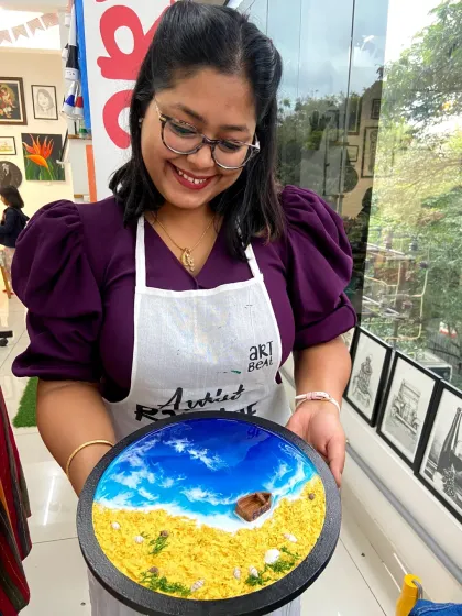 A participant proudly holds up her finished resin beach art, smiling at her beautiful creation.
