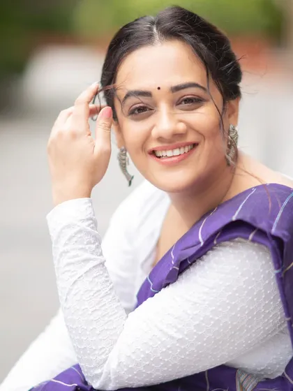 A happy, close-up portrait of Spruha Varad, highlighting the silver jhumkas that complete her contemporary saree look.