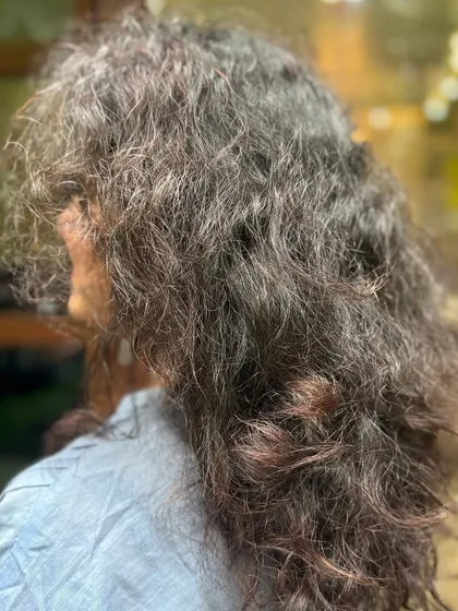 A side view of the hair before the transformation, showing the potential for more definition.