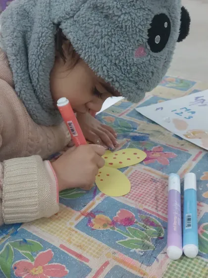 A close-up of a preschooler decorating her craft with dot markers. This is a great activity for developing hand-eye coordination.