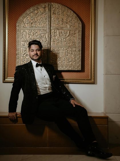 A stylish portrait of the groom, Animesh. His relaxed pose and the elegant, artistic backdrop create a sophisticated and timeless image.