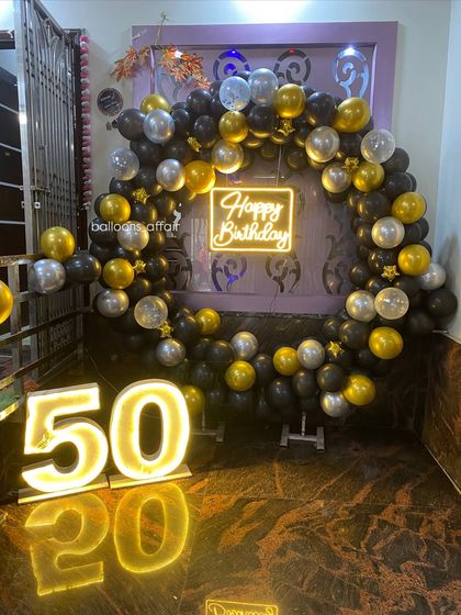 A low-angle shot of the 50th birthday decor, showing the reflection of the marquee lights on the floor.