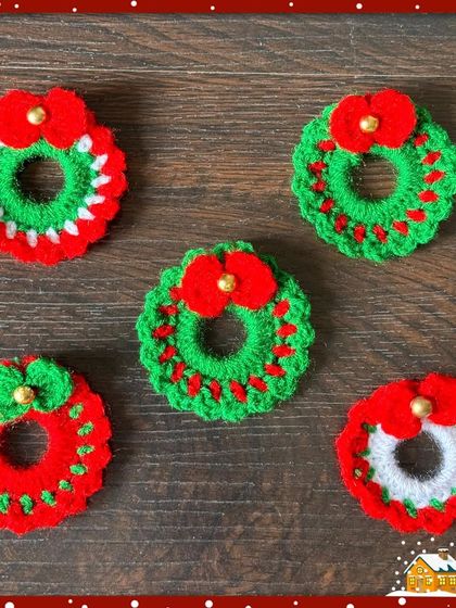 A collection of handmade Christmas wreath brooches. I make them in different color combinations of red, green, and white, each with a small bow or berry detail.