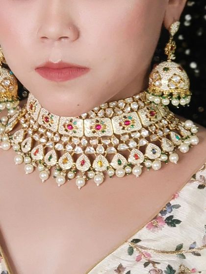 A close-up of a beautiful Navratan-style choker with enamel work and pearl drops. This piece is full of color and perfect for a festive occasion.