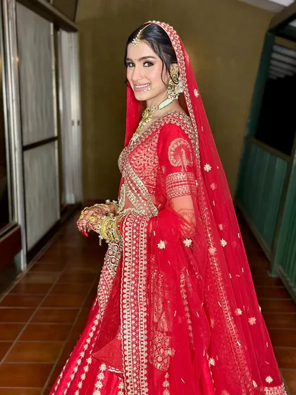 A radiant smile from the bride. Her makeup is classic and clean, with a focus on enhancing her natural beauty in her beautiful red lehenga.