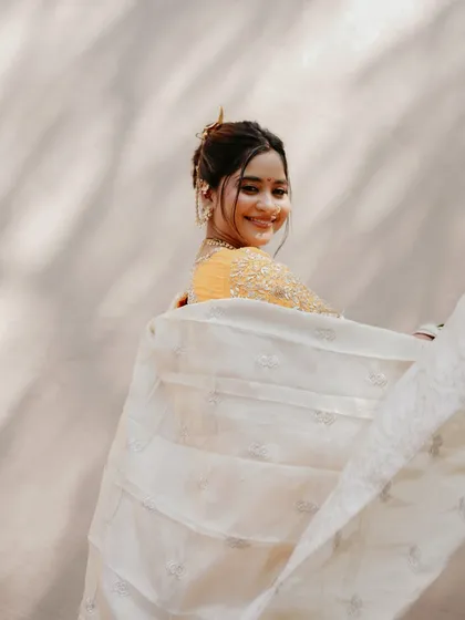 The joy of a bride is infectious. Her playful smile and the flowing 'shela' (dupatta) create a moment of pure happiness.