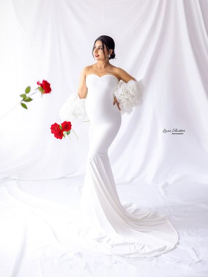 A creative shot with floating red roses, adding a touch of surreal beauty to this elegant white gown portrait.