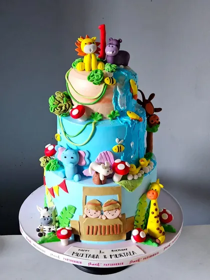 I designed this bright and beautiful jungle safari cake for a first birthday celebration for twins. It's a large, three-tiered whipped cream cake, brought to life with dozens of handcrafted and edible fondant animals, from lions and elephants to a jeep with little explorers.