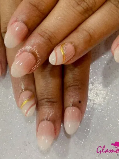 A clean and elegant ombré set. The nails fade from a soft, milky white to a natural nude, with a delicate gold and white swirl on the accent nails for a touch of interest.