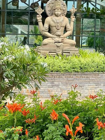 Our gardens are a haven for wildlife, with over 50 species of birds spotted here. The Lord Dhanvantari statue stands amidst the blooms, watching over our sanctuary.