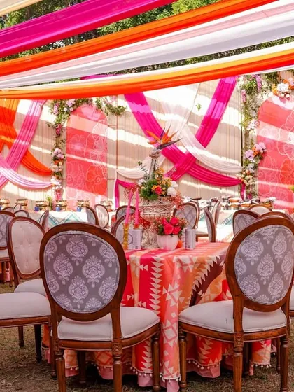 A view of the dining area at the vibrant Mehendi, with tables dressed in colorful printed cloths and surrounded by elegant chairs.
