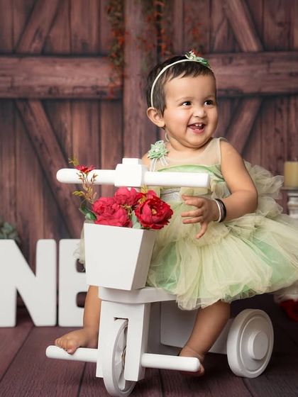Riding into her first year with a huge smile. This little girl in her pretty green dress is having so much fun on her little tricycle during her birthday session.