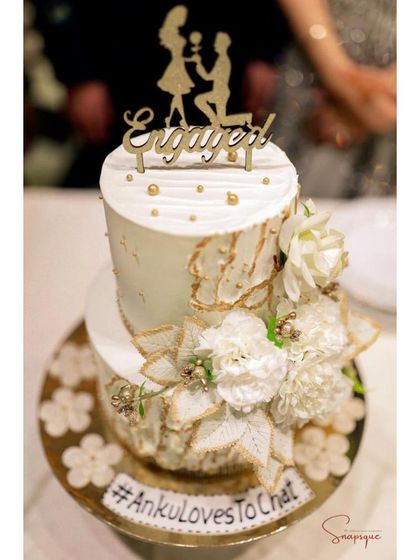 Another shot of the beautiful white and gold engagement cake, showcasing the intricate floral work and personalized details.