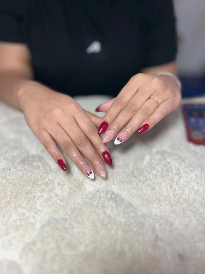 A creative take on a French manicure with red tips and a negative space heart design. This is a fun and romantic look.