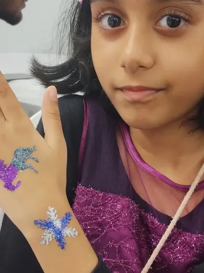 This party guest chose two fantastic designs for her hand. A sparkly unicorn and a shimmering snowflake make for a magical combination, perfect for her party outfit.